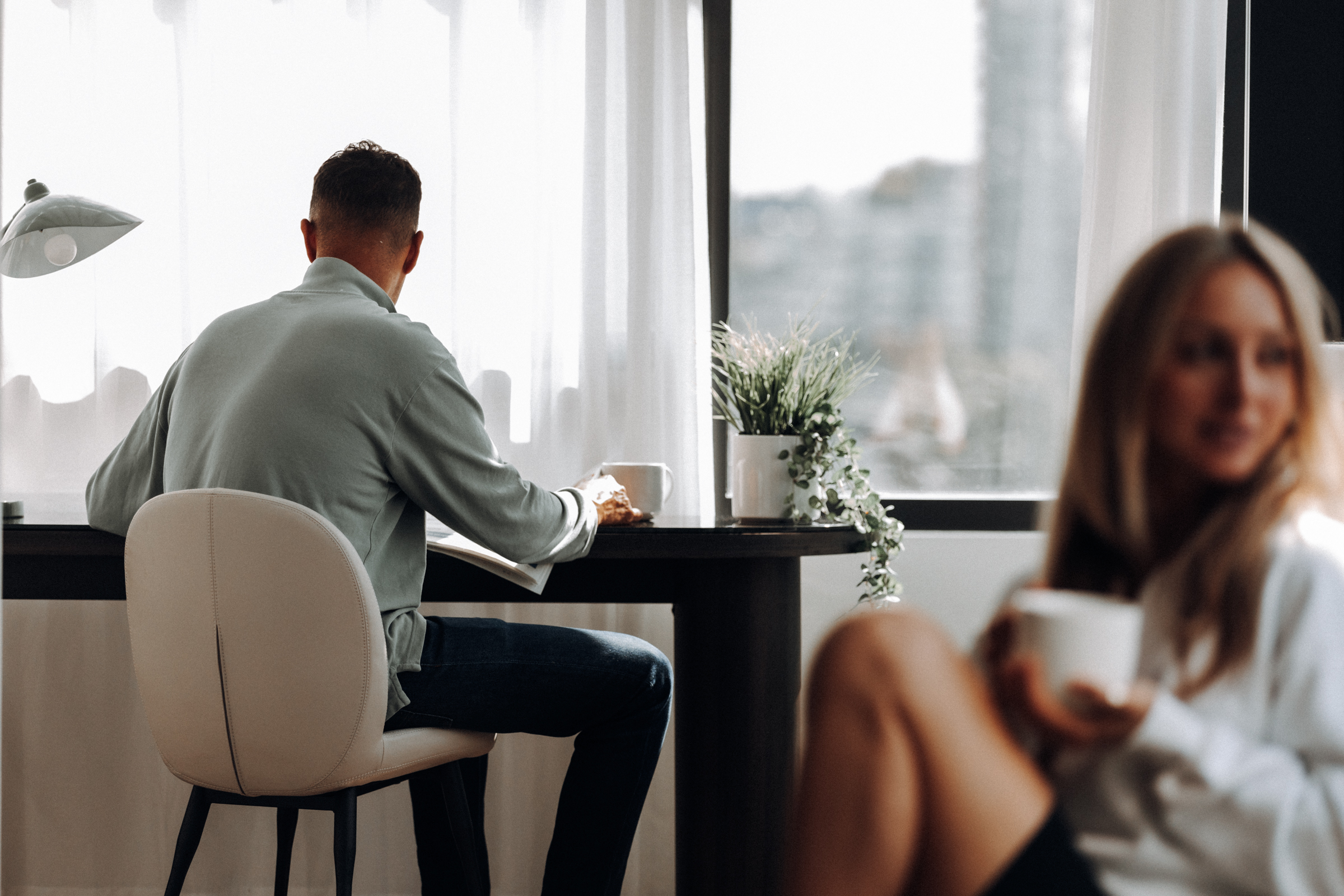 Woman drinking coffee and man at desk in two bedroom hotel suite at Smithe House in Yaletown.